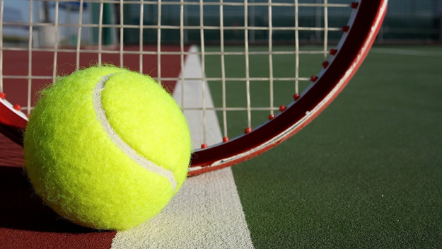 A tennis ball and racket resting on the court. Photo courtesy of Southwest Local Schools website