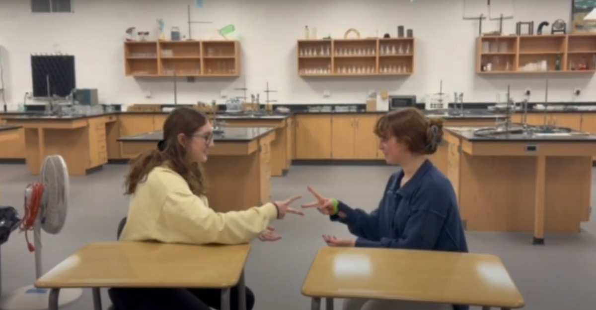 In this screenshot from the excellent informational video, Seniors Maddie Maxfield and Sophia Stinson break the rules by playing the game in Zureick's classroom. Don't worry--he caught them! 