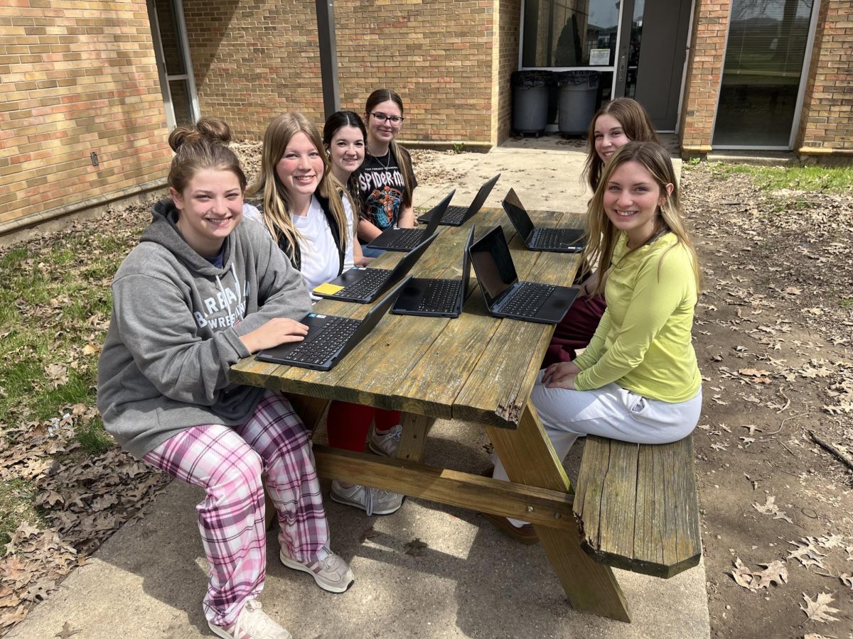 Junior Rylee Dearwester, senior Brett Haugh-Holland, juniors Haylee Price, Addison Schoonover, Lily Foster, and Isabella Thacker enjoy the warm spring day. 