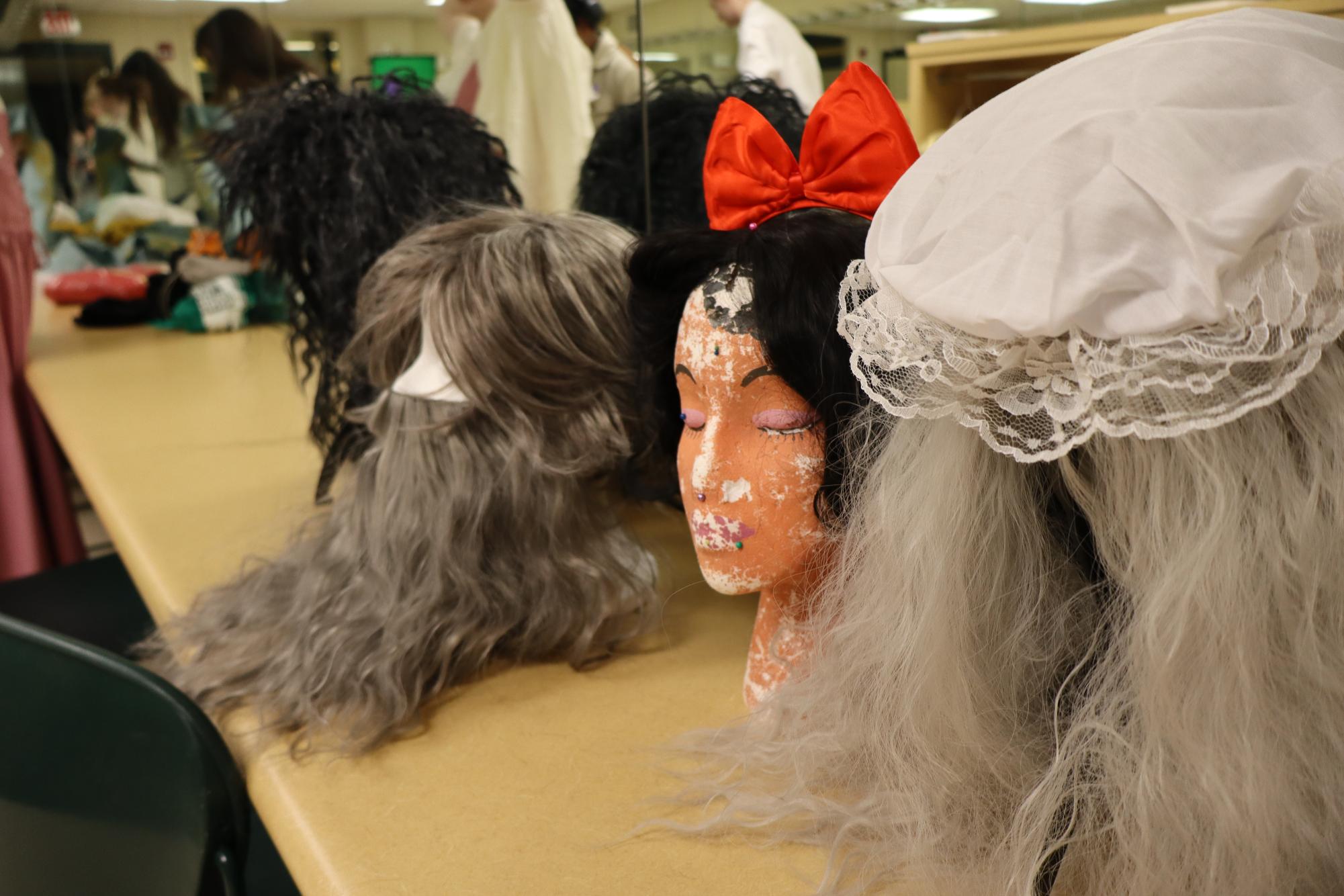 Wigs for the Witch, Mysterious Man, Snow White, and Granny line up and stare down the dressing room