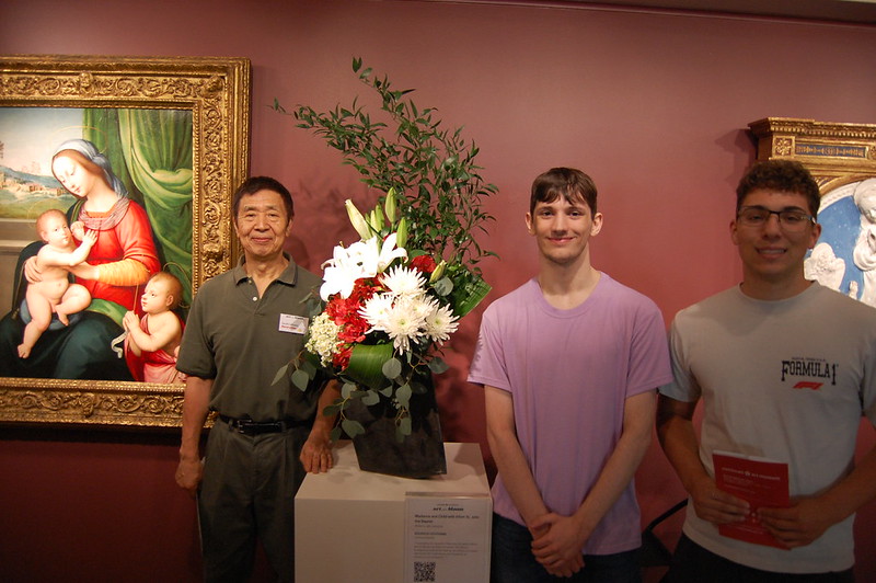 Senior Casey Bertsch, Junior Julian Lambert, and master of floral art Koukichi Uchiyama pose for a photo in front of his art. 